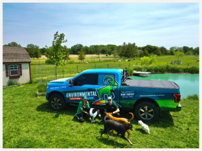 2 workers and dogs in front of a blue pick up truck